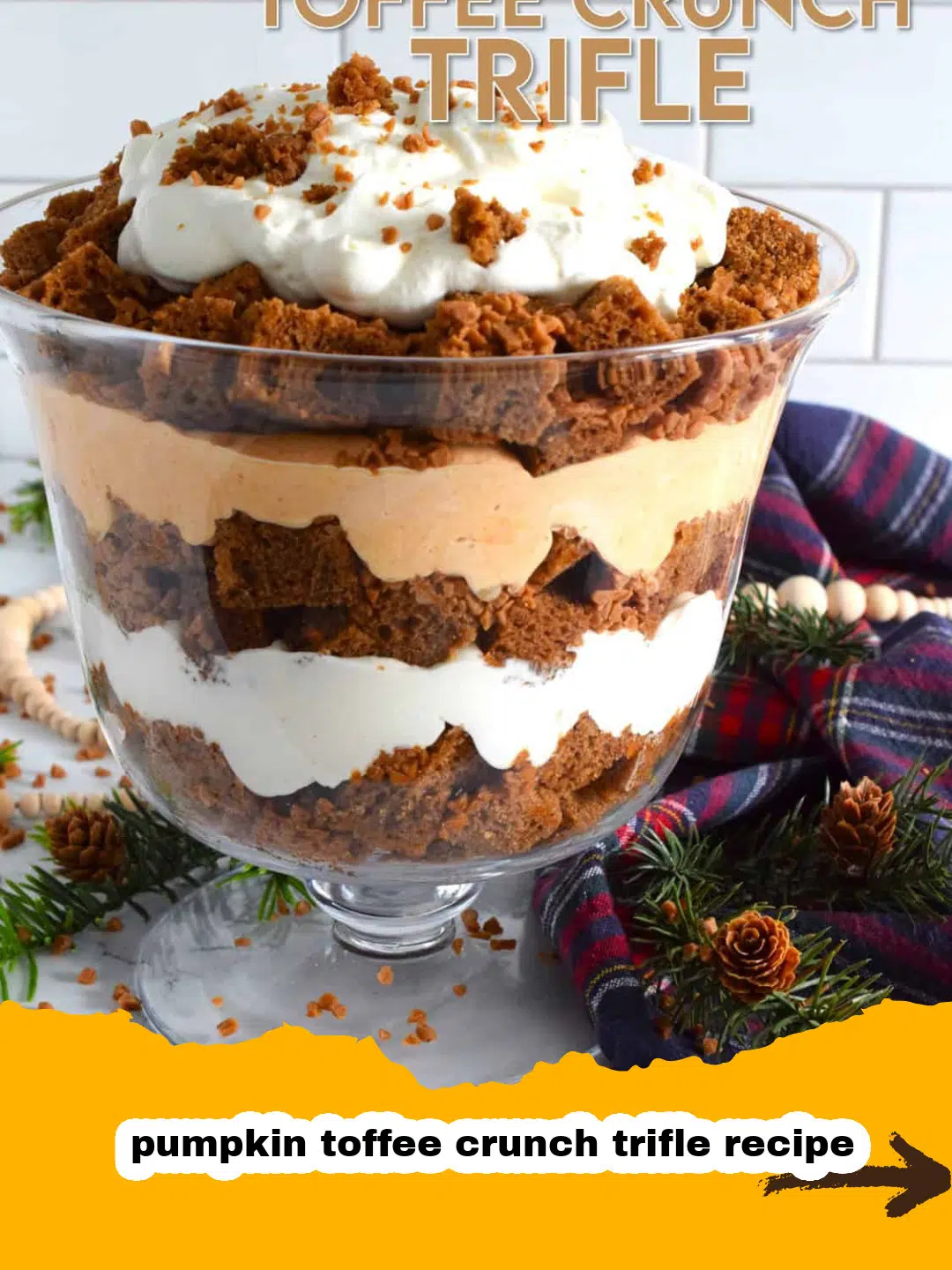 Layered Pumpkin Toffee Crunch Trifle Dessert A clear trifle bowl showcasing the beautiful layers of a homemade pumpkin toffee crunch trifle, with cubed pound cake, orange pumpkin cream, white whipped cream, and scattered toffee pieces.